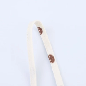 Macro detail of cream-colored woven fabric strap with brown polka dots pattern