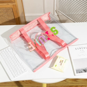 Detail of clear PVC tote bag with pink trim and colorful SMILE chenille patches