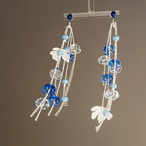 Elegant floral tassel earrings featuring blue beads and silver chains on a T-stand display