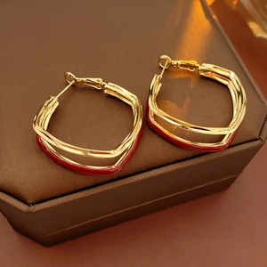 Detail of gold and red double-layer twisted square hoop earrings on a brown gift box