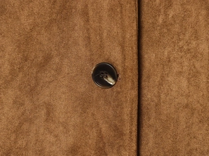 Detailed close-up of brown faux suede blazer fabric and marbled round button texture