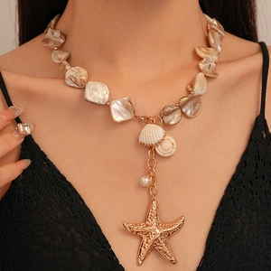 Resort style gold starfish and seashell necklace featuring irregular beads on a model