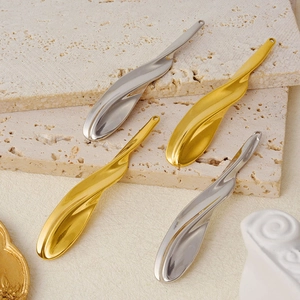 Detail of leaf-shaped wave pendants in gold and silver finish on travertine stone