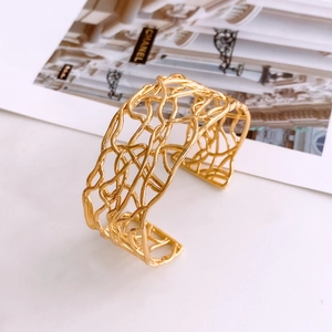 Macro detail of 18K gold-plated open cuff bracelet with abstract woven mesh texture