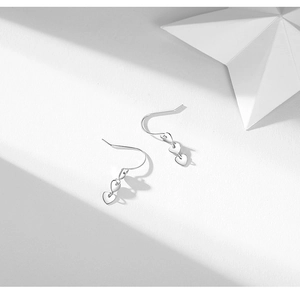 Detail of silver heart tassel drop earrings with polished metallic finish and sleek hooks