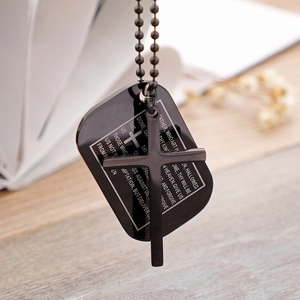 Gros plan d'un pendentif croix en titane noir avec gravure de la prière Notre Père