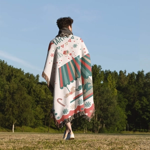 Outdoor lifestyle shot of a thick Christmas knit blanket with tassels on green grass