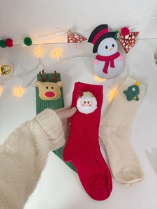 Detail of red Christmas crew sock with Santa Claus felt patch held by hand in a cozy scene