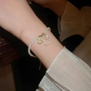 French style pearl bracelet featuring hollow zircon wulu pendants on a model's wrist