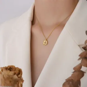 Detailed view of an elegant gold plated floral pendant necklace worn with a white suit