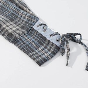 Détail des poignets de chemise à carreaux bleu et gris avec lacets et œillets métalliques