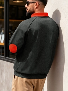 Detail of red color block on collar and sleeve of black fleece quarter-zip sweatshirt