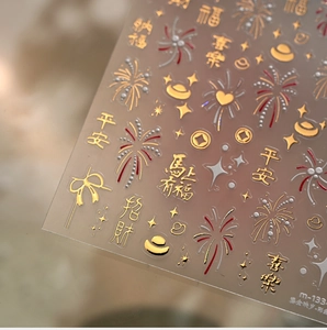 Close-up of Lunar New Year nail stickers with gold embossed fireworks and lucky characters