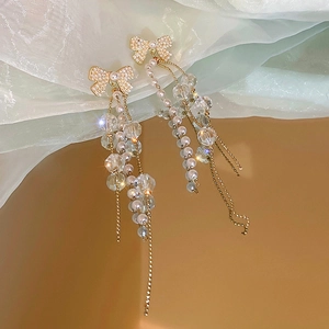 Détail de boucles d'oreilles pendantes avec nœud en perles et pampilles en cristal brillant