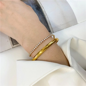 Detail of 18K gold plated minimalist cuff bracelet paired with a sparkling tennis bracelet
