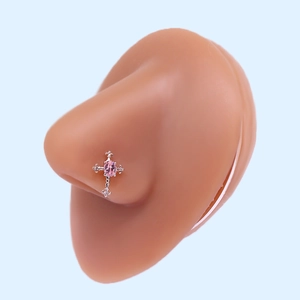 Detail of cross-shaped L-shaped nose stud with oval pink zircon on a silicone nose model
