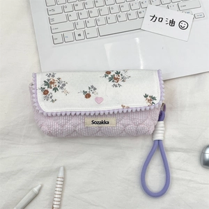 Detail view of a floral quilted pencil case with lavender strap and 'Sozakka' label