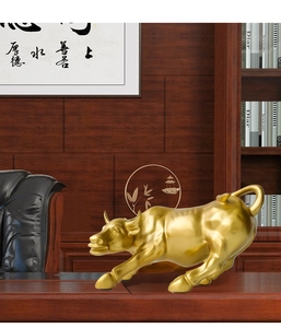 Golden bull statue on mahogany office desk with traditional Chinese calligraphy background
