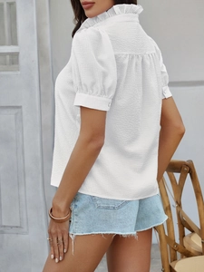 Detalle de blusa blanca texturizada de manga corta con cuello de volantes y botones