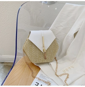 Detail of hexagonal woven straw bag with white leather flap and gold tassel fringe charm