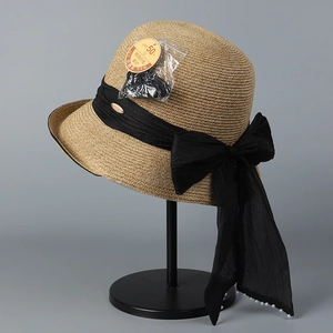 Detail of woven straw hat with large black ribbon bow and elegant pearl accents