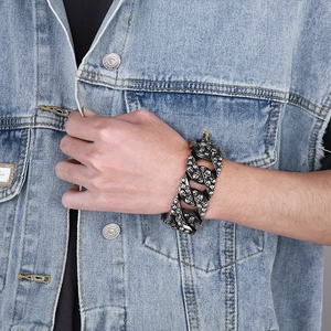 Gros plan sur un bracelet punk en acier avec gravures détaillées de têtes de mort