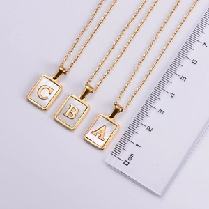 Detailed view of 18k gold plated square initial pendants with ruler measurement