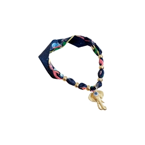 Collana in seta bohémien con ciondolo a forma di elefante dorato e occhio di Allah su fondo bianco