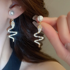 Close-up of sparkling snake-shaped earrings with pearls and micro-paved zircons on model