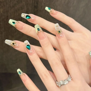 Detail of luxury emerald cat-eye press-on nails with gold accents and green jewels