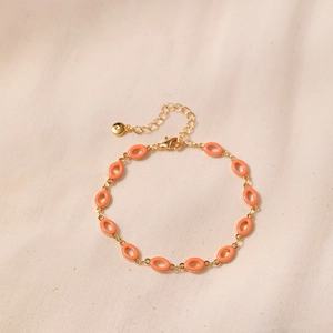 Detail of vintage gold-tone bracelet featuring orange enamel charms and lobster clasp