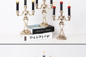 Detailed view of skeleton hand holding black LED candles with red drip for Halloween decor
