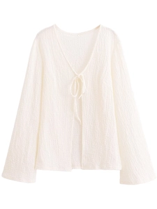 Detail of white tie-front V-neck top showing textured fabric and delicate ribbon closure