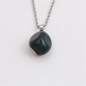 Detail of an irregular natural crystal stone pendant in green and white with silver chain