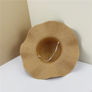 Détail d'un chapeau de paille à large bord ondulé et sangle coupe-vent élastique