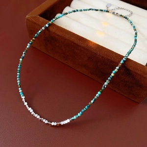 Detail of turquoise beads and silver cubes necklace on brown leather and velvet background