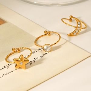 Detailed view of three gold-plated rings with star, moon, and zircon elements on paper
