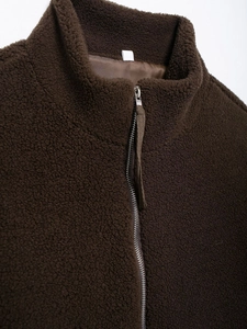 Detail of high collar and metal zipper on brown teddy fleece jacket with plush texture