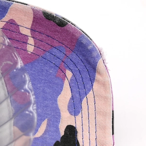 Detailed close-up of purple camouflage cotton cap with distressed edges and blue stitching