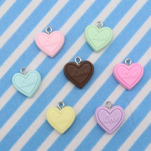 Macro view of colorful resin heart pendants with Love engraving and metal attachment rings