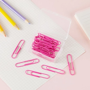 Pink metal paper clips in a clear box with colorful pencils on a pink background