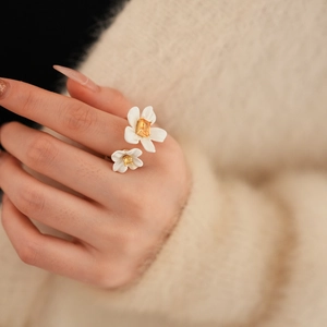 Close-up of gold-plated double flower ring with yellow zircon on beige sweater