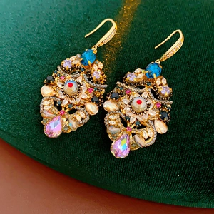 Detail view of vintage gold earrings with colorful crystals on dark green velvet