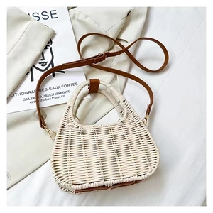 Flat lay of woven crossbody bag with brown leather handles on a white minimalist cloth