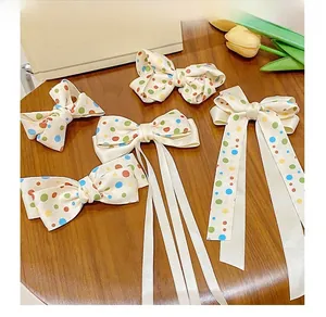 Detailed set of cream satin hair bows with colorful polka dots on a wooden surface