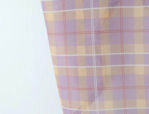 Close-up of light purple and orange plaid chiffon fabric texture with translucent finish