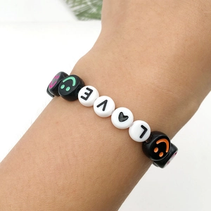 Close-up of handmade bracelet with LOVE letter beads and colorful smiley face patterns