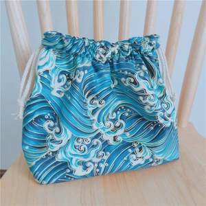 Détail du motif de vagues japonaises sur sac bento en coton épais avec cordon sur chaise bois