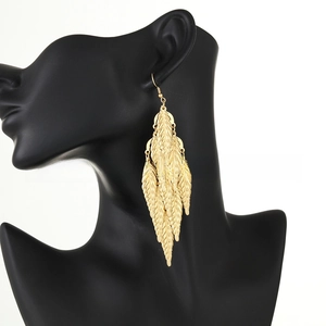 Detail of layered gold leaf tassel earrings with intricate texture on a black mannequin