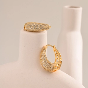 Detail view of gold oval earrings with micro-pave zircons on white ceramic stand
